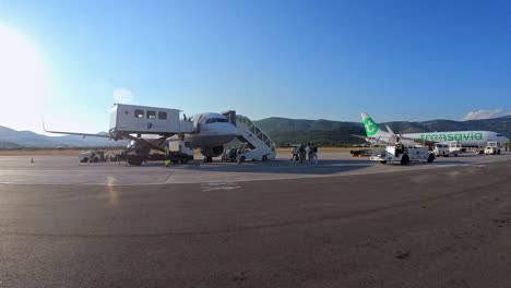 Vehículos-Del-Aeropuerto-Operando-Para-La-Salida-Mientras-Los-Pasajeros-Caminan-Hacia-El-Avión.