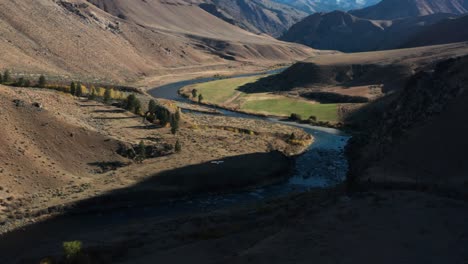 Drone-footage-following-a-backcountry-single-engine-plane-landing-on-a-remote-landing-strip-surrounded-by-mouintains-and-a-river-in-the-Frank-Church-River-of-No-Return-Wilderness-in-Idaho