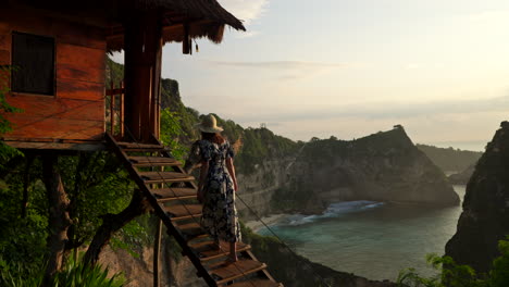 Female-influencer-walks-up-stairs-of-famous-tree-house,-Nusa-Penida,-Bali