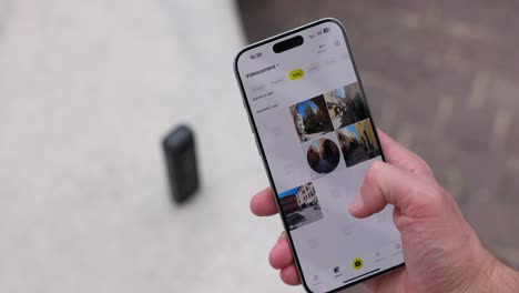 Close-up-hand-holding-smartphone-and-scrolling-through-digital-photo-album-app