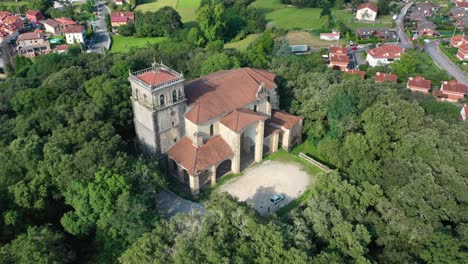 Orbitalflug-Mit-Drohne-über-Die-Kirche-San-Vicente-Aus-Dem-16.-17.-Jahrhundert-In-Rio-Frio,-Kantabrien.-Sie-Befindet-Sich-Auf-Einem-Mit-Eichen-Bewachsenen-Hügel-Und-Wir-Sehen-Ihren-Prächtigen-Glockenturm,-Spanien