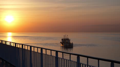 The-ferry-sails-in-the-calm-Baltic-Sea-and-passes-with-the-ship-next-to-it,-a-gentle,-calm-sunset