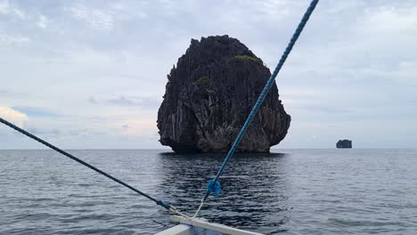 Boast-Sailing-by-Standalone-Limestone-Rock-in-Sea-Water,-El-Nido,-Philippines