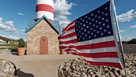 Faro-Del-Puerto-De-Grafton-Con-Banderas-Americanas-Ondeando-En-El-Viento-En-Cámara-Lenta-A-Lo-Largo-Del-Río-Mississippi,-Illinois,-Estados-Unidos