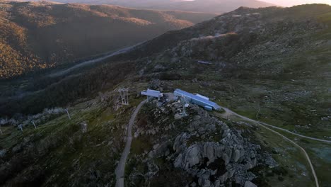 Thredbo-ski-resort-chairlift-during-dry-summer-aerial-with-forest-mountains-at-sunrise,-Snowy-Mountains,-NSW,-Australia