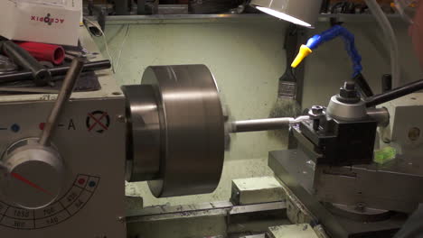 This-video-shows-a-lathe-operated-in-a-machine-shop-that-is-in-the-process-of-cutting-metal-from-a-round-bar-with-metal-chips-flying-off