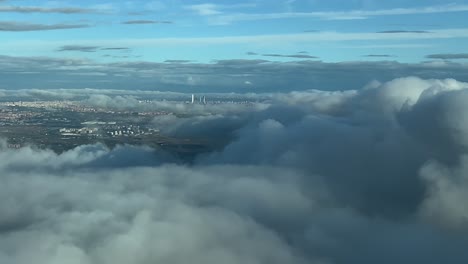 Vista-Aérea-Lejana-De-La-Ciudad-De-Madrid,-España,-Tomada-Desde-La-Cabina-De-Un-Avión-Volando-Sobre-Algunas-Nubes-Acercándose-Al-Aeropuerto