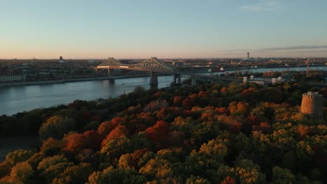 aerial-view-over-Jean-Drapeau-Parc-in-Montreal-with-a-view-on-Jacques-Cartier-Bridge-and-the-Levis-Tower-during-fall-season-at-sunset