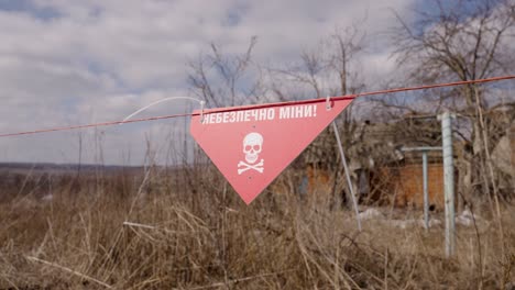 Attention-mines-warning-sign-with-skull-and-crossbones-logo-hang-off-wire-fence