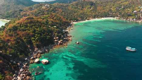 Aerial-drone-shot-capturing-a-Tropical-Island-bay-view-with-boats-on-clear-turquoise-blue-water-in-Thailand