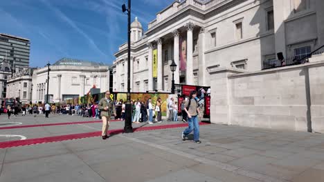London's-Trafalgar-Square,-visitors-patiently-queue-for-entry-into-the-esteemed-National-Portrait-Gallery