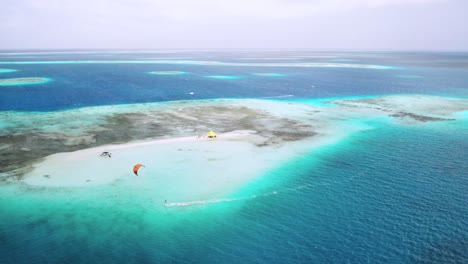 Kite-surfers-gliding-on-the-turquoise-waters-around-sardina-island,-showcasing-serene-tropical-beauty,-aerial-view