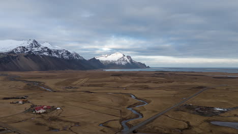 Un-Vasto-Paisaje-Islandés-Cerca-De-Hofn,-Con-Montañas-Nevadas-Y-Campos-Abiertos,-Vista-Aérea