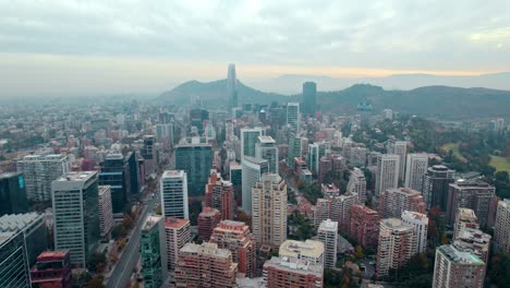 Aerial-Establishing-Cityscape-of-Santiago-de-Chile-El-Golf-Neighborhood-Mountain-Cordillera-Background