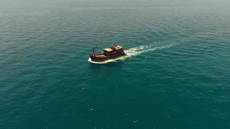 Aerial-drone-shot-of-an-old-school-pirate-boat-cruising-in-the-middle-of-the-turquoise-sea-water-in-Thailand