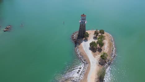 Solitary-lighthouse-on-headland-with-scenic-tropical-beach