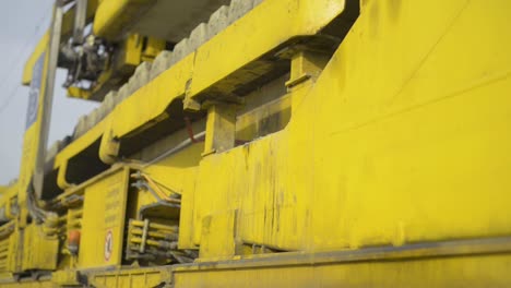 Close-up-of-a-yellow-maintenance-train-on-tracks-during-the-day,-focus-on-machinery-details