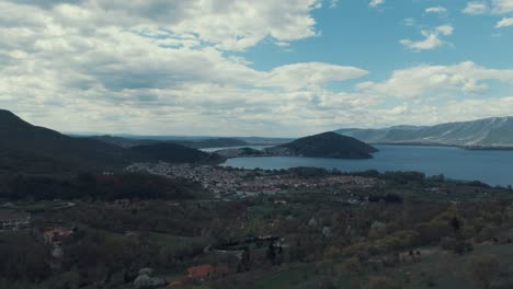 Drohnenaufnahme-über-Einem-Dorf-Auf-Einem-Hügel,-Rote-Dächer,-Kleine-Häuser,-Sonniges-Wetter,-Blauer-See,-Malerische-Berge,-4K-Video