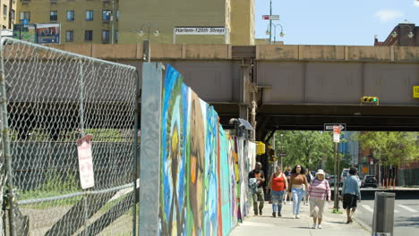 New-Yorker-Gehen-An-Einem-Unbebauten-Grundstück-In-Der-Nähe-Einer-Hochbahn-In-Harlem,-New-York,-Vorbei