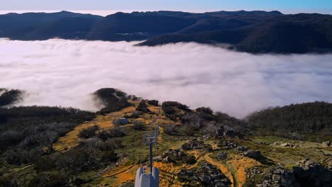 Drone-tilt-reveal-of-ski-chairlift-and-mountain-fog-during-summer-at-Thredbo,-Snowy-Mountains,-NSW,-Australia