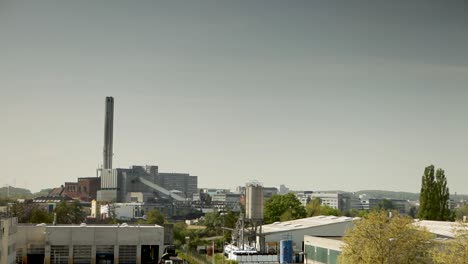 Eine-Weite-Stadtansicht-Mit-Einer-Industrieanlage-Mit-Hohen-Schornsteinen-Unter-Einem-Klaren-Blauen-Himmel