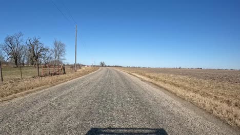 POV---driving-on-a-narrow-county-road-in-a-rural,-agricultural-area-of-western-Illinois-in-early-spring-on-a-bright-day