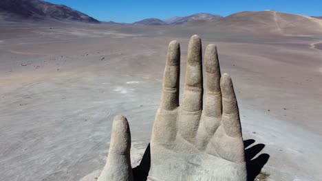 Huge-roadside-sculpture-of-hand-in-remote-sand-desert-in-Chile,-aerial