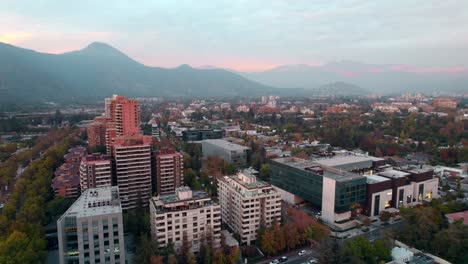 Distrito-De-Vitacura-Al-Atardecer-Con-Los-Andes-Al-Fondo,-Paisaje-Urbano,-Vista-Aérea