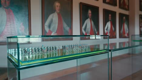 Glass-display-of-miniature-soldiers-with-historic-officer-portraits-in-the-background-at-Trakoscan-Castle,-Croatia