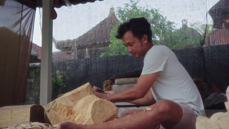 Joven-Artista-Balinés-Tallando-Una-Máscara-De-Barong-En-La-Madera-Con-Un-Cincel-Y-Un-Mazo.