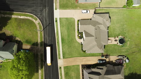 A-school-bus-driving-through-a-quiet-suburban-neighborhood-in-collierville,-tennessee,-aerial-view