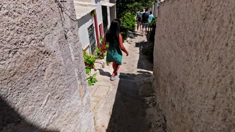 Turistas-Caminando-Por-Calles-Estrechas-De-Anafiotika,-Cámara-Lenta-Siguen-Un-Disparo-Desde-Atrás