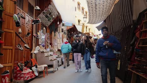 Tourists-and-local-people-walking-narrow-alleyways-of-old-Medina-souk-in-Fez,-Morocco