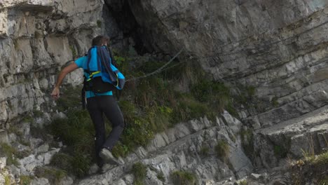 A-Man-Holds-Onto-the-Safety-Chain-While-Climbing-the-Rocky-Terrain-of-Monte-Resegone-in-Lombardy,-Italy---Tracking-Shot