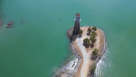 Solitary-lighthouse-on-headland-with-scenic-tropical-beach