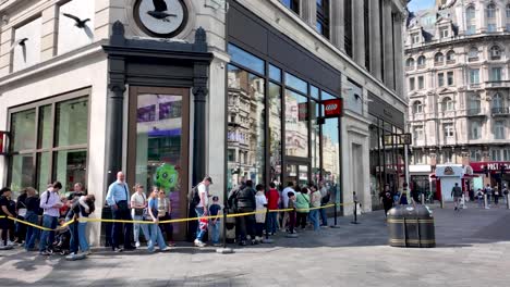 In-London's-Leicester-Square,-visitors-patiently-line-up-for-entry-into-the-Lego-store,-embodying-the-spirit-of-anticipation-and-excitement-for-a-playful-and-immersive-experience