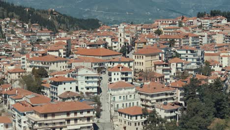 Drones-Volando-De-Cerca,-Sobre-Un-Pueblo-En-Una-Colina-Verde-En-Europa,-Tejados-Rojos,-Casitas,-Clima-Soleado,-Vídeo-4k-De-Grecia