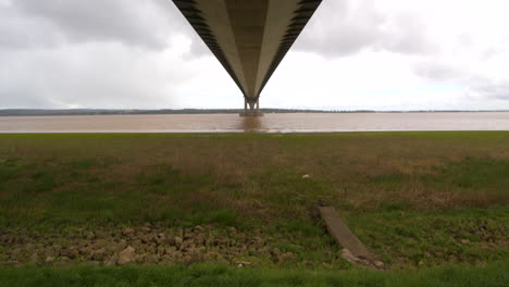 Wide-shot,-tilting-down-from-the-bridge-deck-of-the-Humber-bridge-onto-the-Humber-estuary-on-the-south-shore