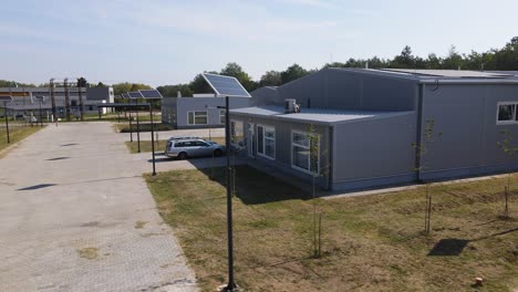 Toma-Aérea-Sobre-Una-Calle-Con-Paneles-Solares-Y-Un-Nuevo-Edificio-Industrial-Al-Fondo,-Tompa,-Hungría