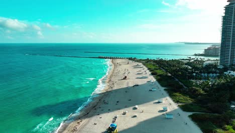 Flying-right-over-the-sand-and-Pacific-Ocean-on-Miami-South-Beach-at-dusk-aerial-view