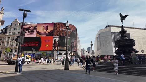 On-a-sunny-morning,-pedestrians-gather-in-the-bustling-pedestrian-area-surrounding-Piccadilly-Circus-in-London