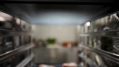 Close-up-of-raw-fish-fillets-on-a-baking-tray-being-inserted-into-an-oven