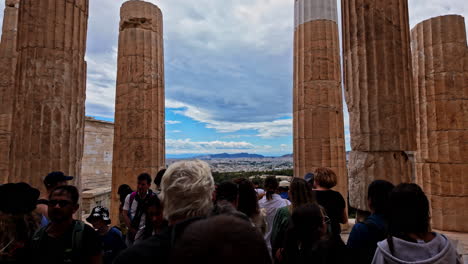 Slow-motion-shot-of-tourists-walking-around-the-Monument-of-Agrippa-and-Propylaia,-Acropolis-in-Athens,-Greece-on-a-cloudy-day