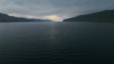 Dolly-En-Vuelo-Bajo-Sobre-El-Lago-Ness-Captura-Una-Luz-Radiante-Que-Emerge-De-Las-Nubes-En-Las-Tierras-Altas-De-Escocia.