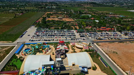Aerial-drone-pan-shot-from-right-to-left-over-amusement-rides-in-Attica-Zoological-Park,-Athens,-Greece