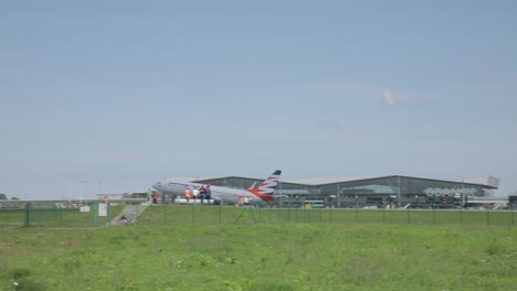 Pan-shot-of-Smartwings-airplane-taking-off-toward-HSM-Global-delivery-vans