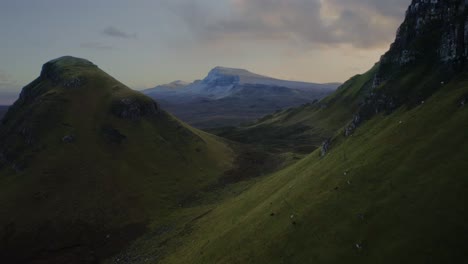 Slow-dolly-in-flight-through-Scotland-Highlands-reveals-a-snowy-distant-mountain,-Isle-of-Skye,-Quirang-trek