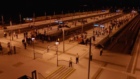 Vista-Nocturna-Elevada-De-Una-Bulliciosa-Estación-De-Tren-Con-Gente-Esperando