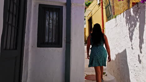 Mujer-Caminando-Por-El-Estrecho-Callejón-Del-Barrio-Histórico-De-Anafiotika-En-Plaka,-Atenas,-Grecia