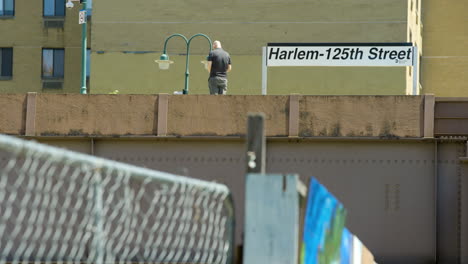 Single-Man-on-Elevated-Train-Platform-in-Harlem,-New-York-City